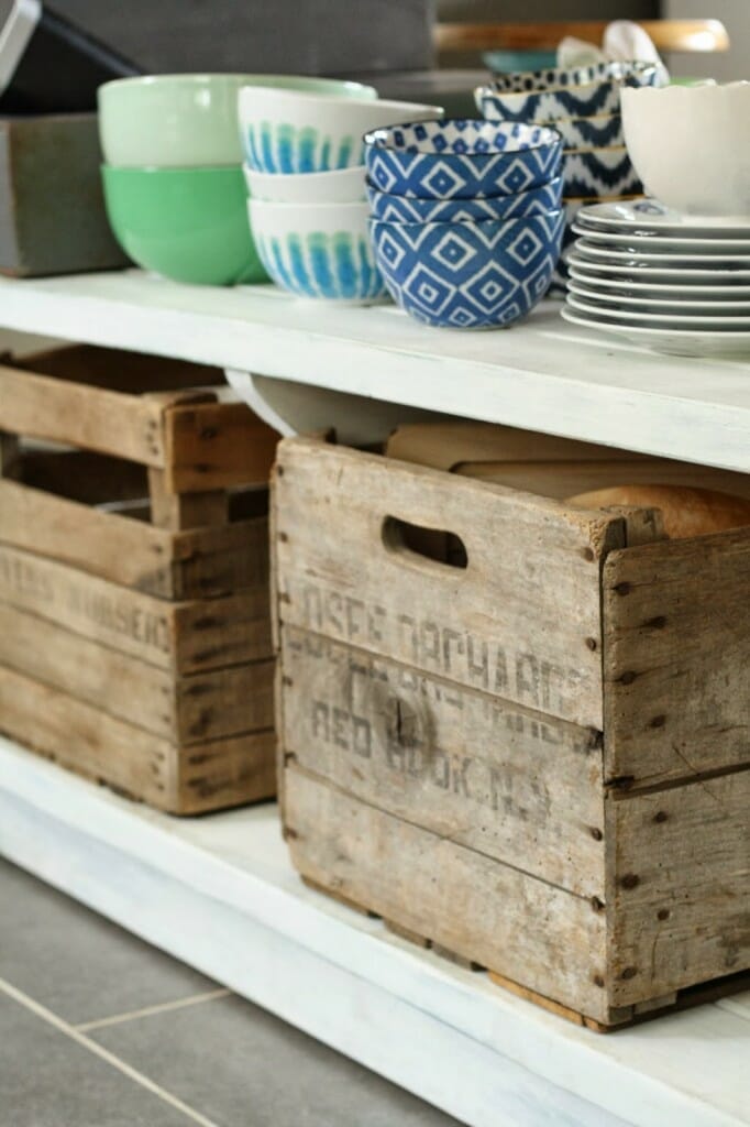 open shelving on island for every day dishes and vintage crates for storage