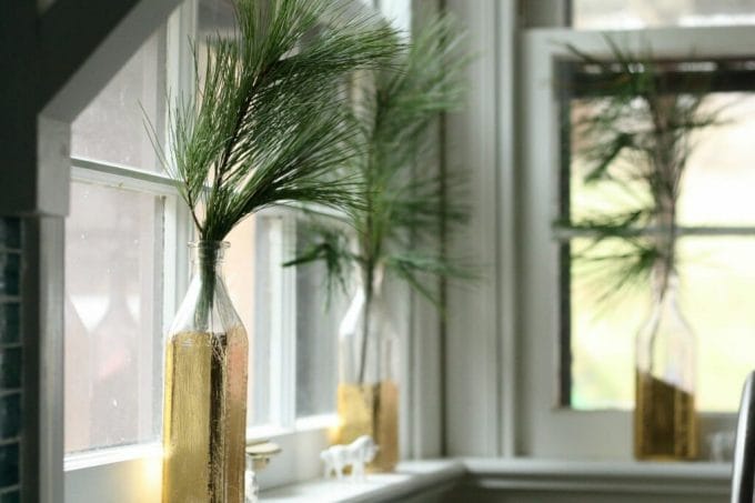 kitchen window with gold leafed bottles and evergreen