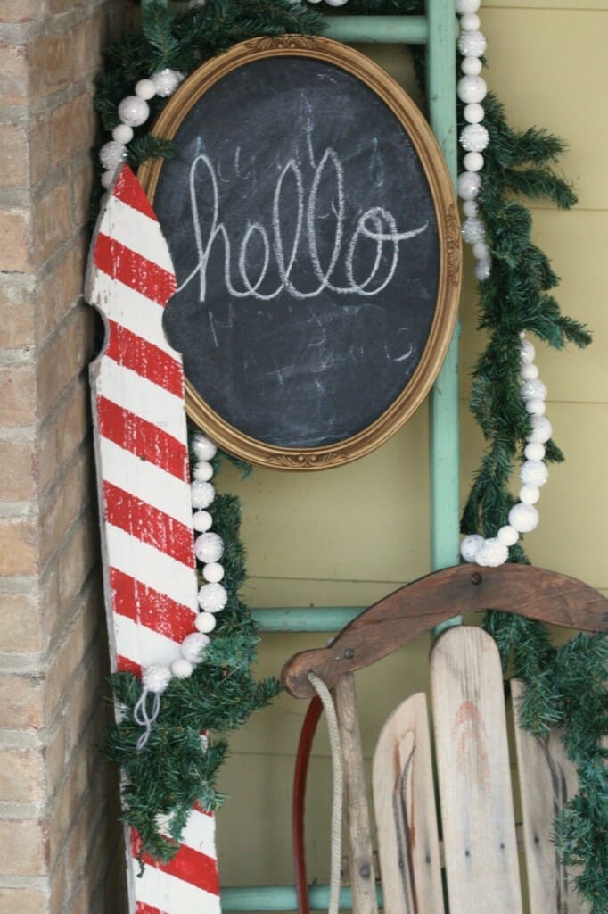 Christmas porch entry with candy cane picket, ladder, garlands, chalkboard