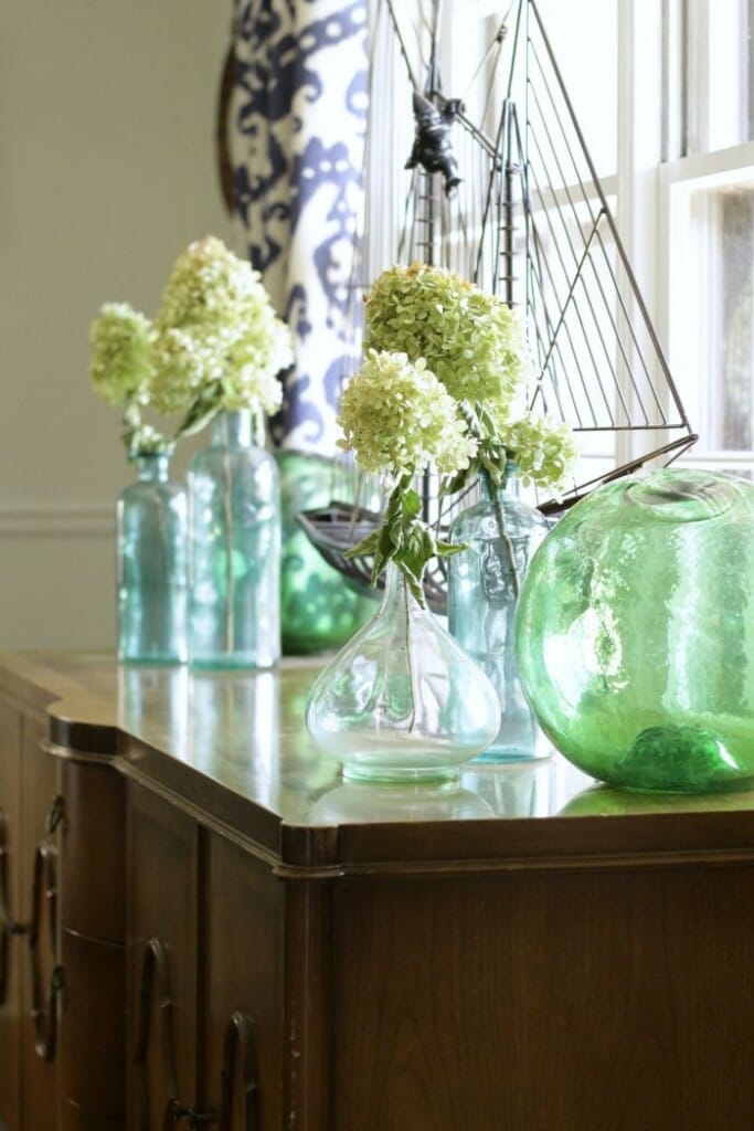 Dining Room Sideboard with green and blue glass and dried hydrangeas