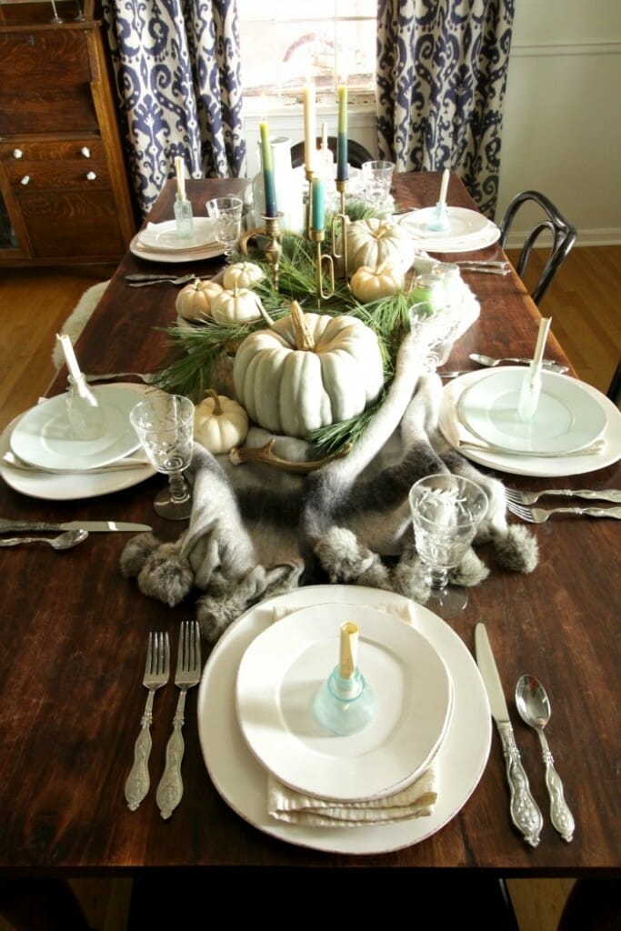Blue & Green Thanksgiving table with a blanket, pines, and pumpkins, and message in a bottle place cards