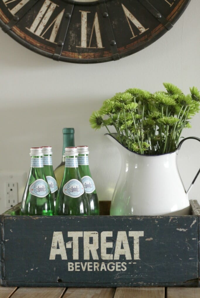 Vintage crate with green glass bottles and enamel pitcher and flowers