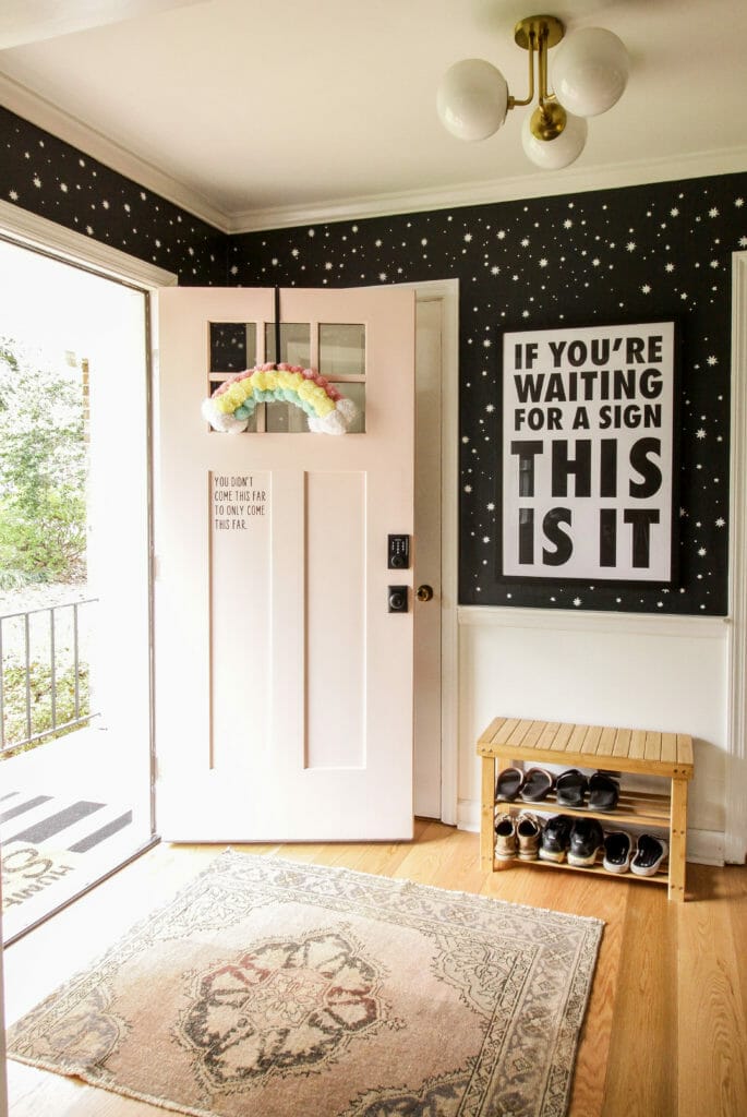small modern entry with black and white star stencil walls, and pink door, and vintage rug
